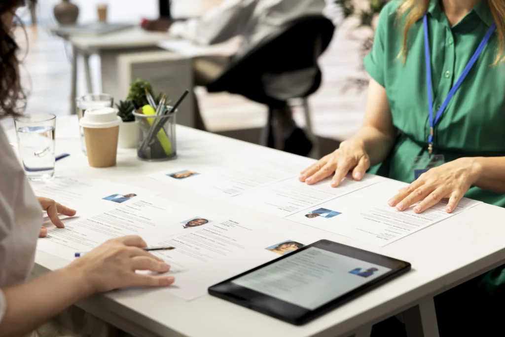 HR staff members using tablet to look at CVs and do background checks to potential job applicants. Headhunters use device to read resumes, attracting qualified candidates for vacant startup position