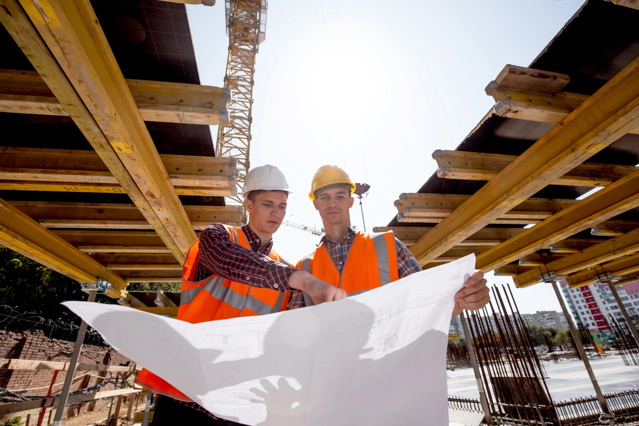 Structural engineer and architect dressed in shirts, orange work vests and helmets